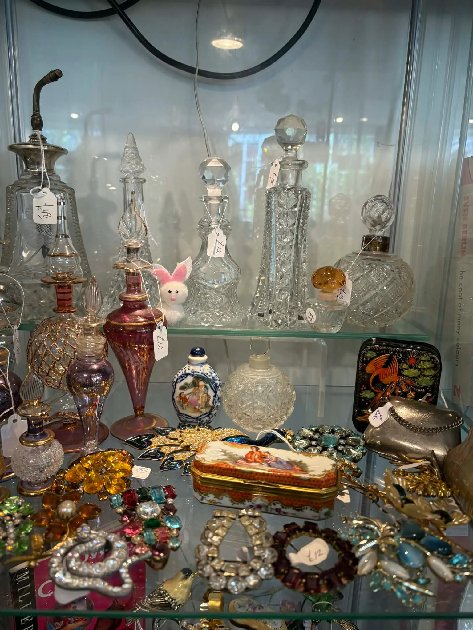 Crystal perfume bottles and vintage jewellery in a display cabinet at Bridge Antiques Centre, Truro